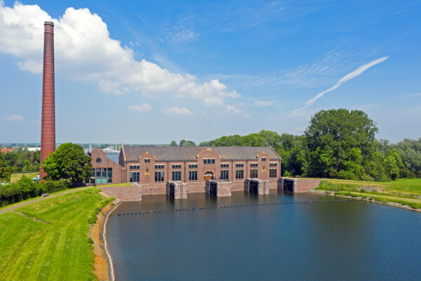 Een gemaal met water ervoor en groen aan de zijkanten.