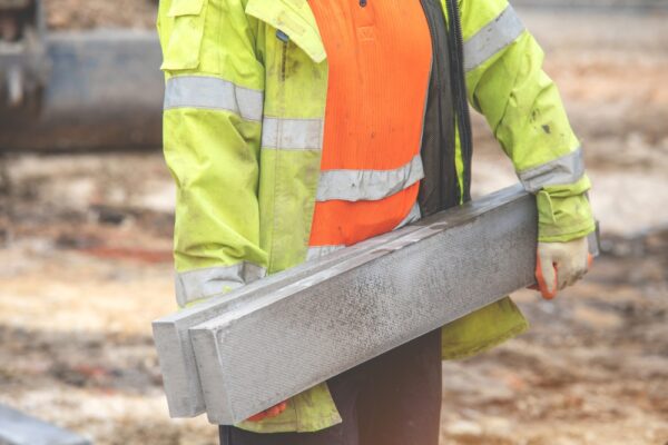 Persoon in werkkleding die twee betonnen bliezen vast houd.