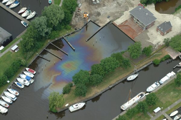 Een haven met een grote olievlek in het water.