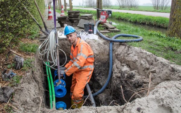 Een monteur werkt in de sleuf.