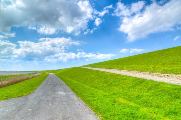 Een dijk met een weg en een hoge graskant.